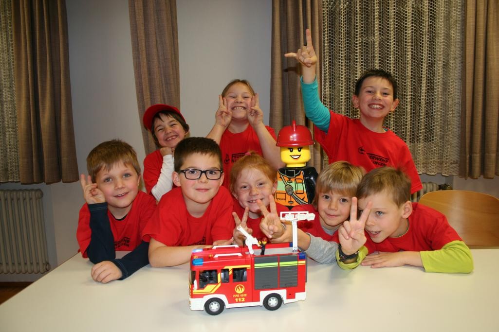 Mehrere Kinder und Legofigur "Betty" mit Spielzeug Feuerwehrauto